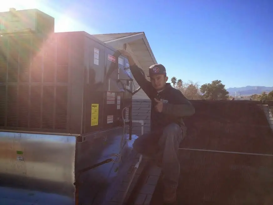 HVAC technician performing HVAC Inspection on a rooftop unit in Mission